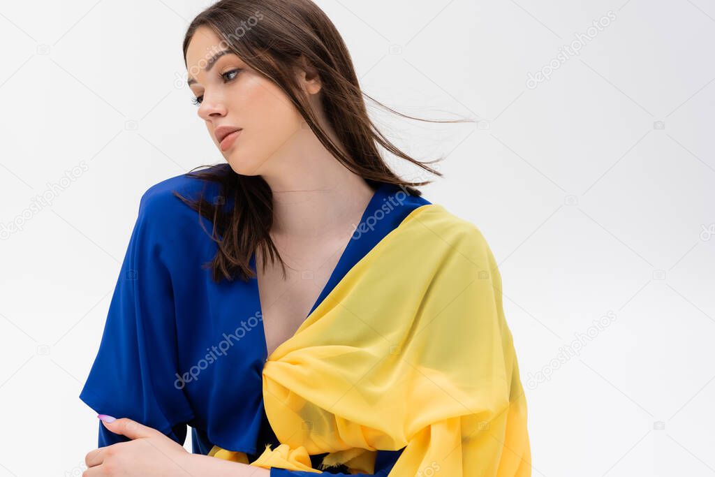 patriotic ukrainian young woman in blue and yellow outfit looking away isolated on grey