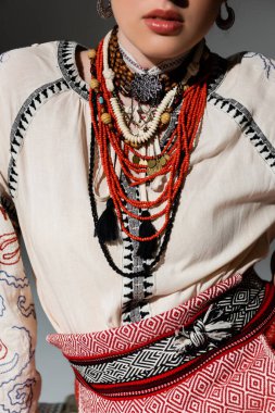 cropped view of ukrainian woman in traditional clothes with beads isolated on grey