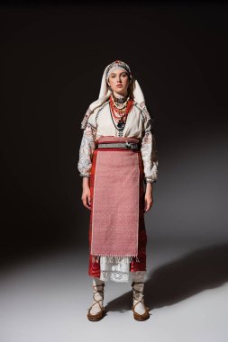 full length of young ukrainian woman in traditional dress with ornament posing on black