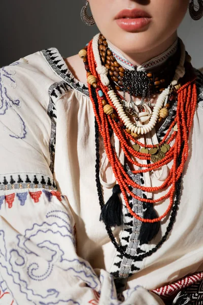 partial view of ukrainian woman in traditional clothes and floral red wreath isolated on grey