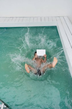 top view of man with computer falling in outdoor pool