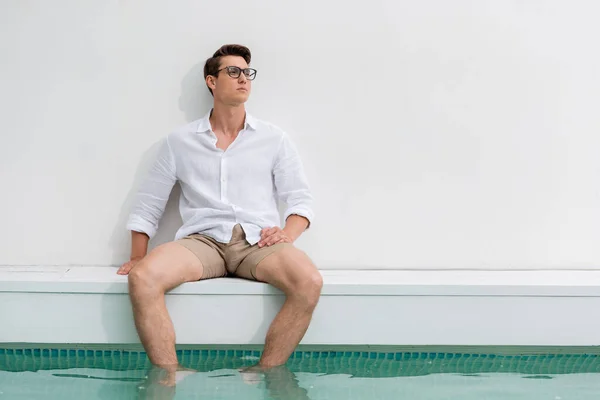 Dreamy Man Eyeglasses Looking Away While Sitting Feet Pool — Φωτογραφία Αρχείου