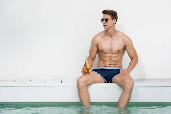 Athletic Man Sunglasses Sitting Bottle Beer Pool White Wall — Stock fotografie