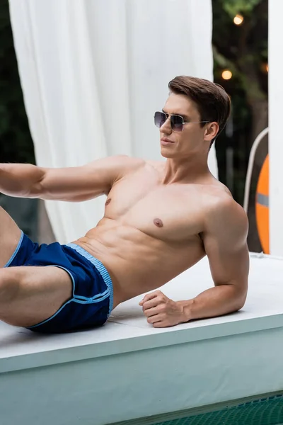 Shirtless Man Swimming Trunks Sunglasses Relaxing Poolside — стоковое фото