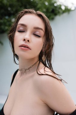 Portrait of stylish woman with wet hair closing eyes at resort 