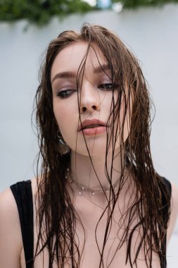 Trendy brunette woman with wet hair looking away at resort 