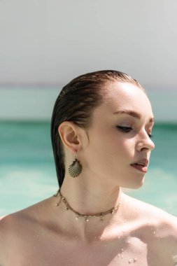 portrait of pretty woman in accessories sunbathing near swimming pool  