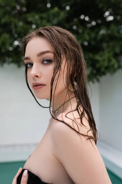 Brunette woman with wet hair looking at camera at resort