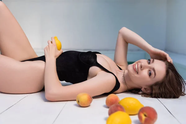 Cheerful Young Woman Black Swimsuit Lying Fresh Fruits Poolside — 스톡 사진