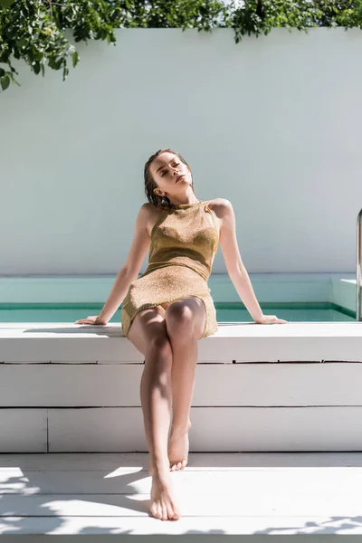 Full Length Barefoot Stylish Woman Golden Dress Swimwear Sitting Poolside — Φωτογραφία Αρχείου