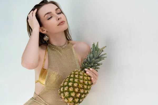 Young Woman Golden Summer Dress Holding Ripe Pineapple White Wall — стоковое фото