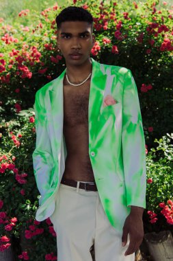 young african american man looking at camera while posing in trendy clothes in park
