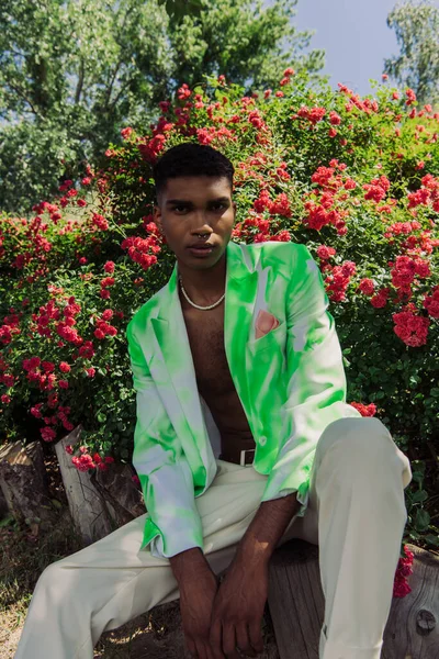 African American Man Stylish Blazer Beads Sitting Blossoming Bushes Looking — Stockfoto
