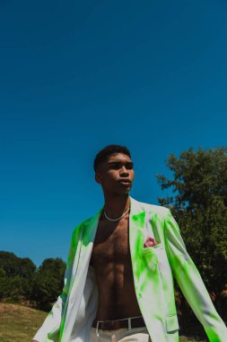 african american man in beads and white and green blazer outdoors