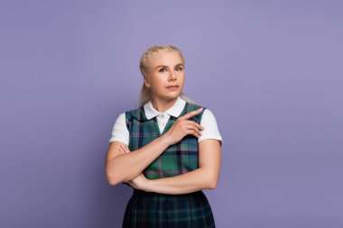 Student in vest and shirt pointing with finger isolated on purple 
