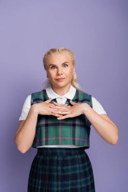 Confused student in plaid vest looking at camera isolated on purple 