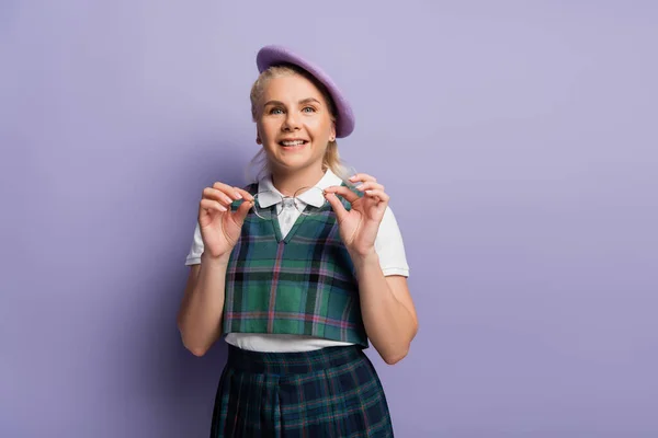 Positive Blonde Student Beret Holding Eyeglasses Purple Background — Zdjęcie stockowe