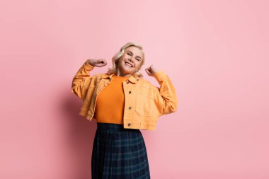 Happy woman stretching and looking at camera on pink background