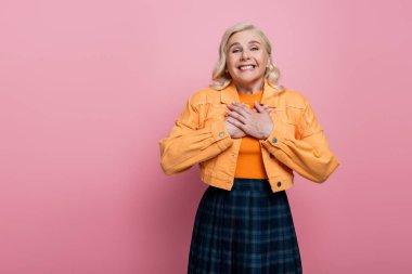 Excited blonde woman looking at camera isolated on pink 