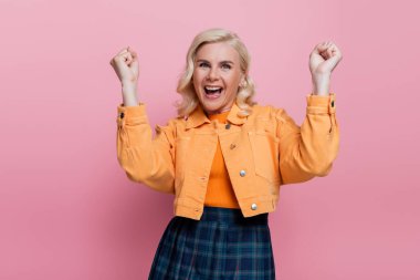 Pretty and excited woman showing yes gesture isolated on pink 
