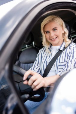 Positive blonde woman looking at camera in auto during driving courses 