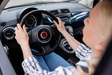 Blurred woman holding steering wheel of car during driving course 