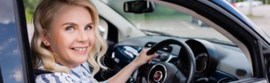 Smiling beginner sitting in car during driving course, banner 