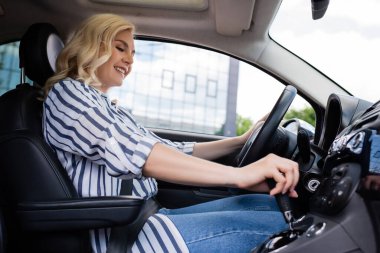 Cheerful blonde beginner driving car during course 