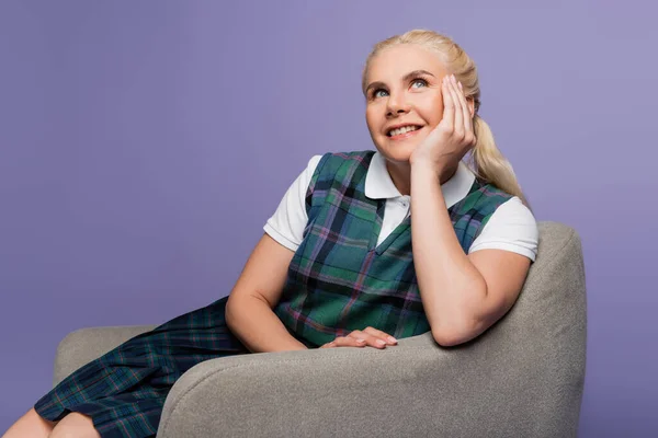 Positive Blonde Student Uniform Looking Away Armchair Isolated Purple — Stockfoto