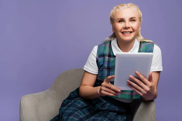 Positive Student Using Digital Tablet While Sitting Armchair Isolated Purple — стоковое фото