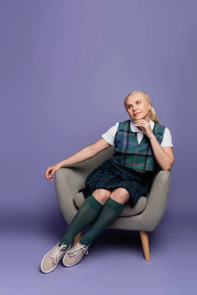 Dreamy Student Plaid Uniform Sitting Armchair Purple Background — стоковое фото