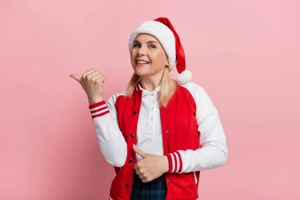 Smiling Woman Santa Hat Pointing Finger Isolated Pink — Foto de Stock