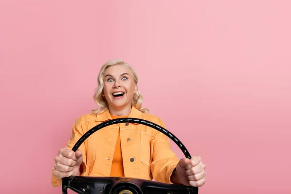 Amazed Blonde Driver Holding Steering Wheel Looking Camera Isolated Pink — Φωτογραφία Αρχείου