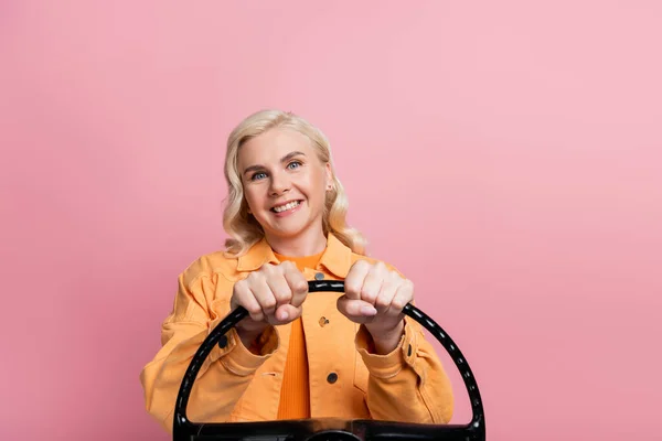 Cheerful Blonde Driver Jacket Holding Steering Wheel Isolated Pink — стоковое фото