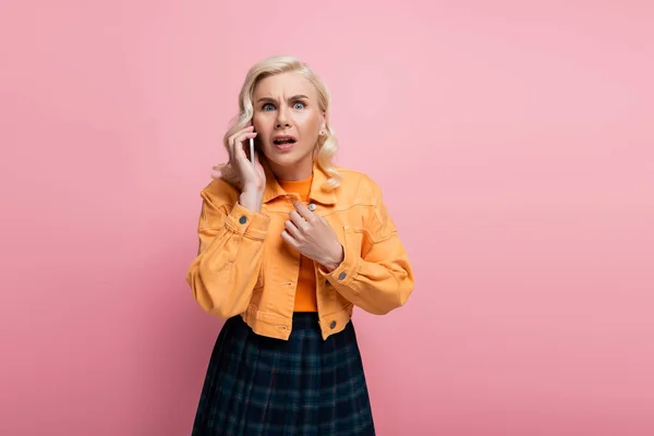 Scared Blonde Woman Looking Camera While Talking Smartphone Isolated Pink — Stok fotoğraf