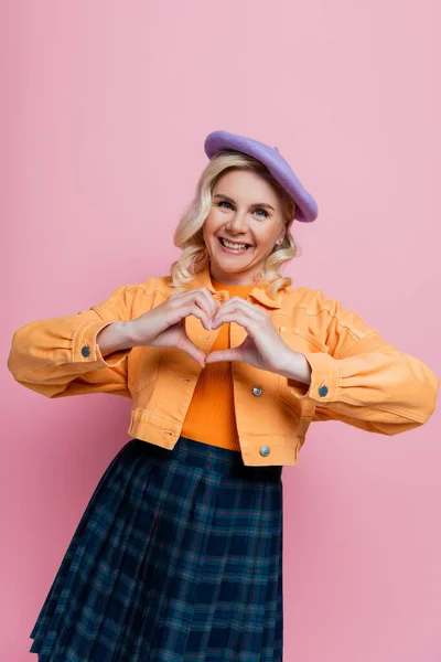 Positive Blonde Woman Beret Showing Heart Sign Isolated Pink — стоковое фото