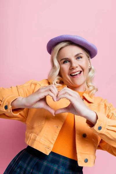 Positive Blonde Woman Beret Showing Heart Sign Isolated Pink — Zdjęcie stockowe