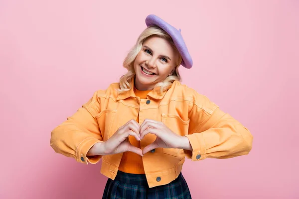 Smiling Blonde Woman Beret Jacket Showing Love Sign Isolated Pink — Zdjęcie stockowe