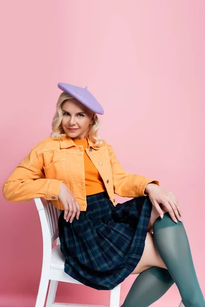 Trendy Young Woman Beret Sitting Chair Pink Background — Foto de Stock