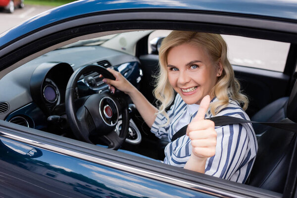 Positive driver showing like gesture during driving course in car 