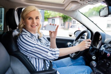 Positive blonde driver holding license in auto 