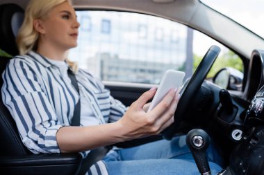 Blurred driver holding cellphone while driving car 