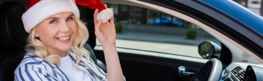 Positive driver in santa hat looking at camera in auto, banner 