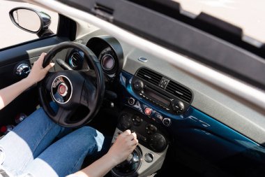Cropped view of woman in jeans driving car 