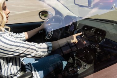 Side view of driver pushing buttons on panel of auto 