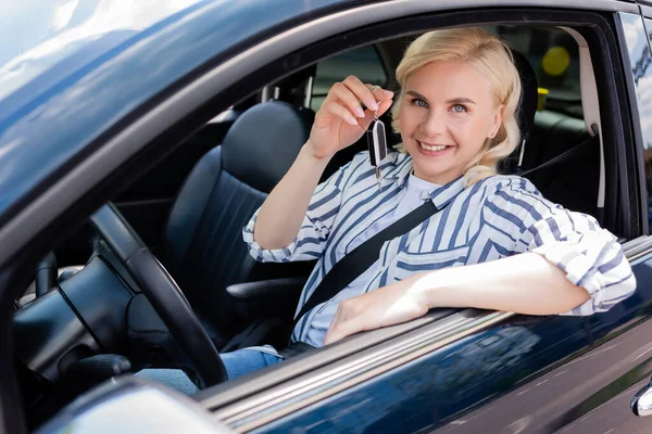 Cheerful Blonde Driver Holding Key While Sitting Auto — Stockfoto