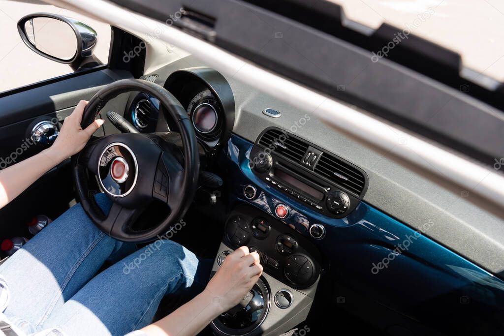 Cropped view of woman in jeans driving car 