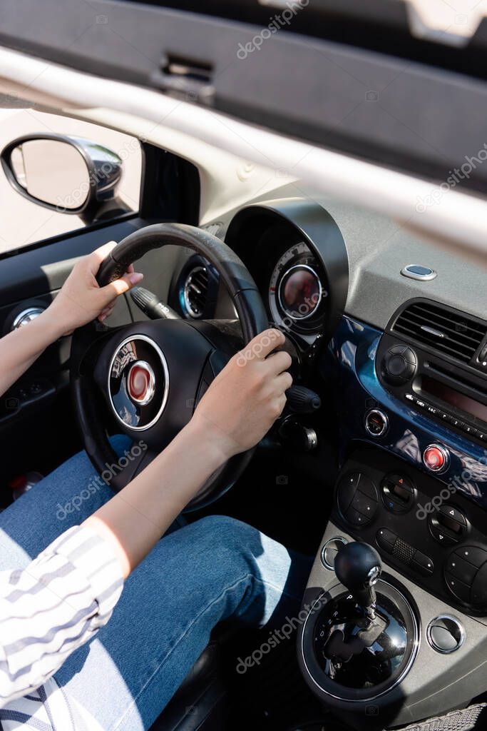Cropped view of woman in casual clothes driving auto 