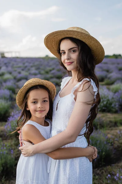 Brunette Woman Daughter Straw Hats Hugging Looking Camera Lavender Meadow — Stock fotografie