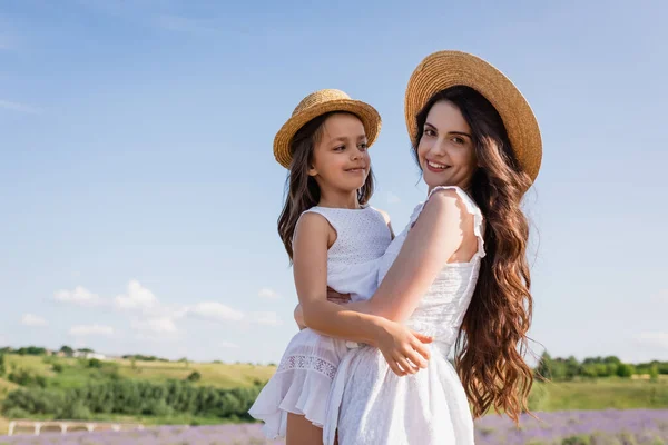 Brunette Woman Straw Hat Smiling Camera While Holding Daughter Countryside — Stock fotografie